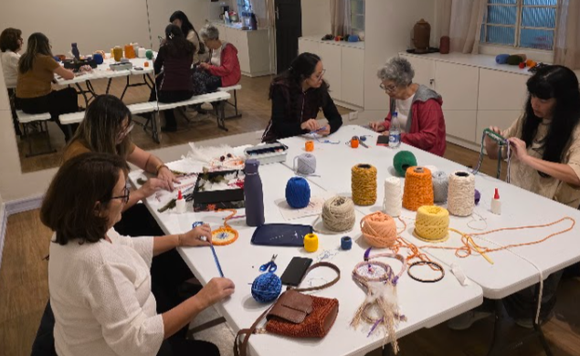 Grupo criando junto numa mesa, com materiais de artesanato à mostra